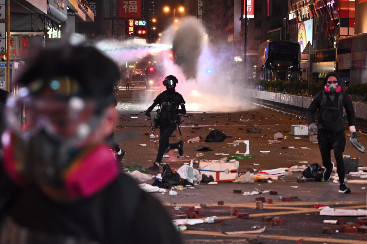 Protesters run as police deploy water cannon at the Mong Kok district of Hong Kong on November 11, 2019. 
