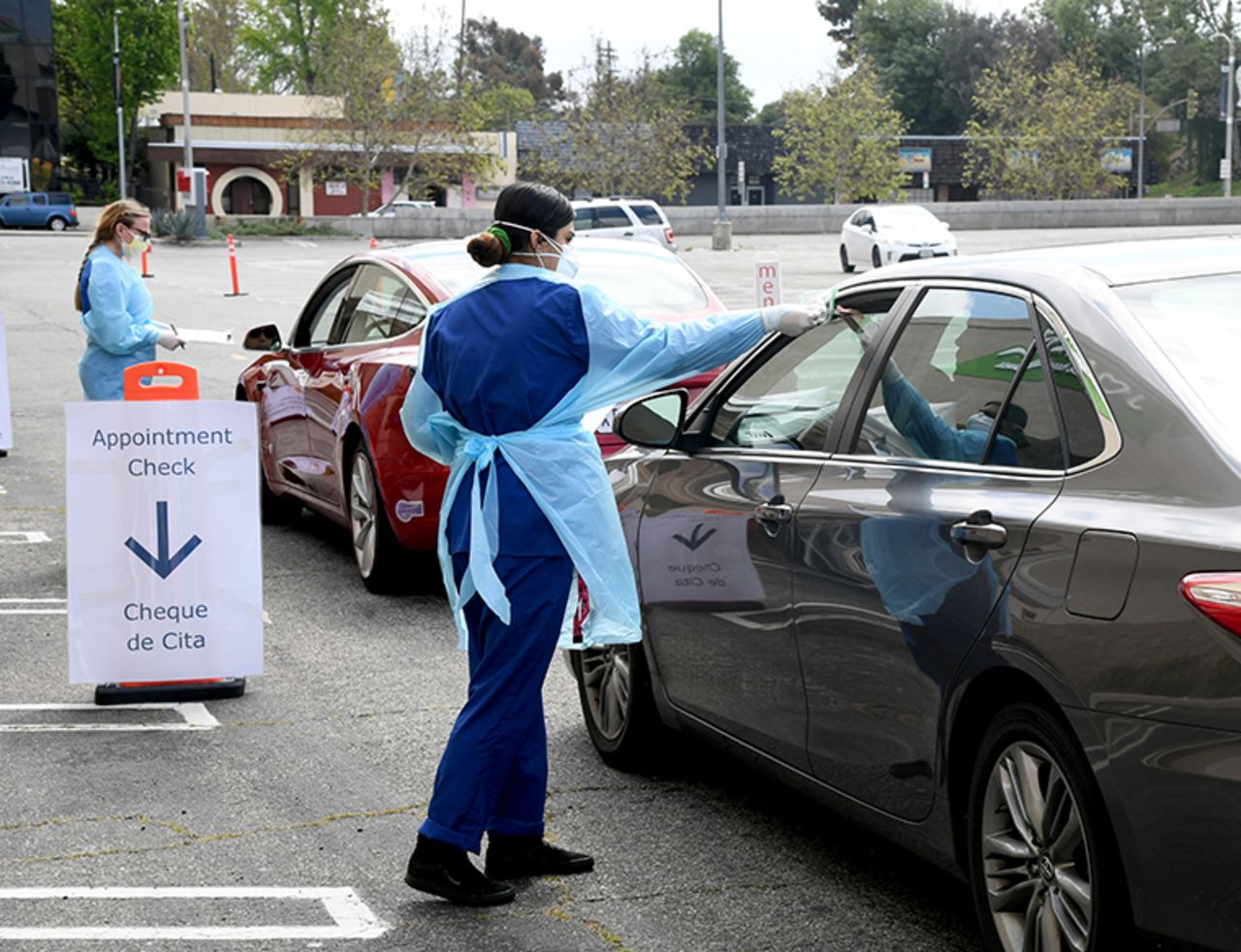 Workers wearing personal protective equipment gather the tests administered from people's cars as Mend Urgent Care hosts a drive-thru testin at the Westfield Fashion Square on Monday,April 13, in Los Angeles