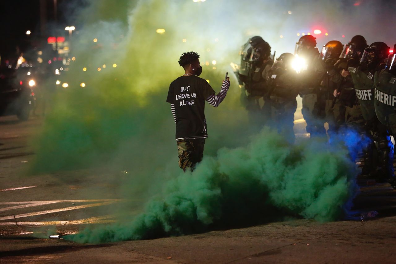 A protester walks through smoke while filming Hillsborough County sheriff's deputies in Tampa, Florida, on May 30.