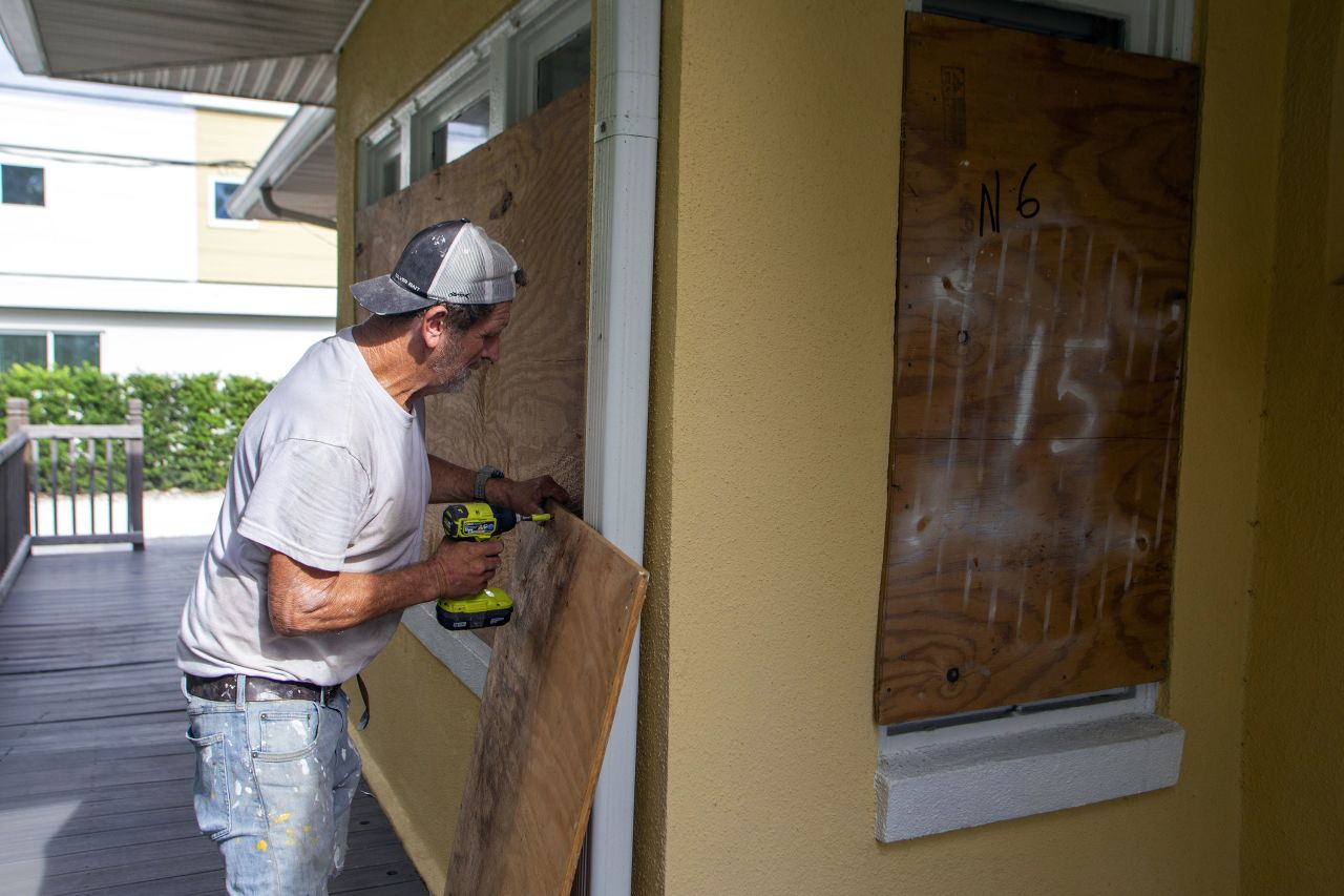 A resident places wooden boards to protect a house in St. Petersburg, Florida, on Monday.