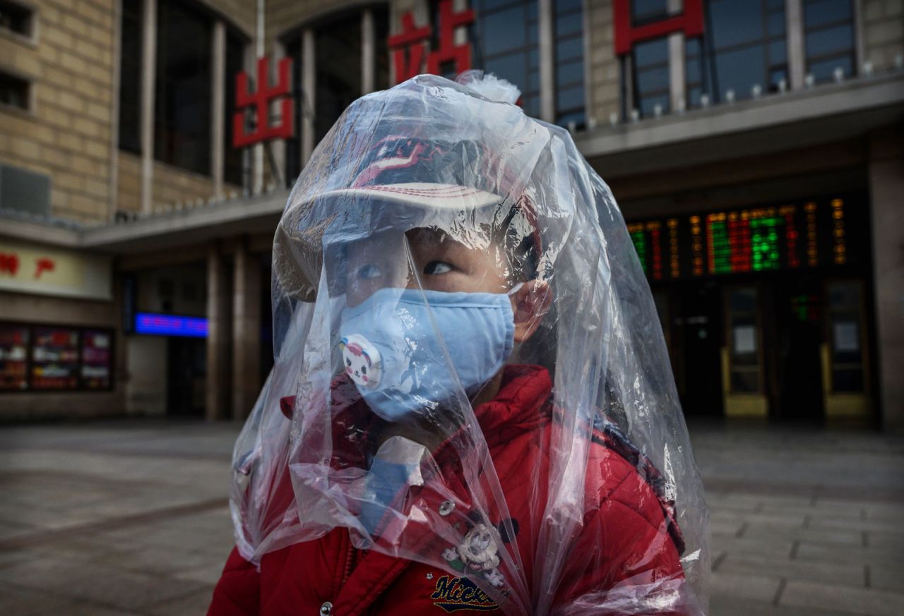 A boy is covered in a plastic bag amid the coronavirus outbreak as he arrives from a train at Beijing Station on February 12, 2020. 