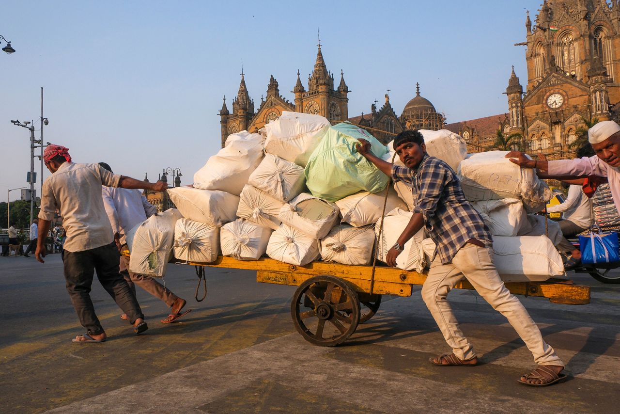 Workers push a cart with packages along a road in front of Victoria Terminus, in Mumbai on April 18.