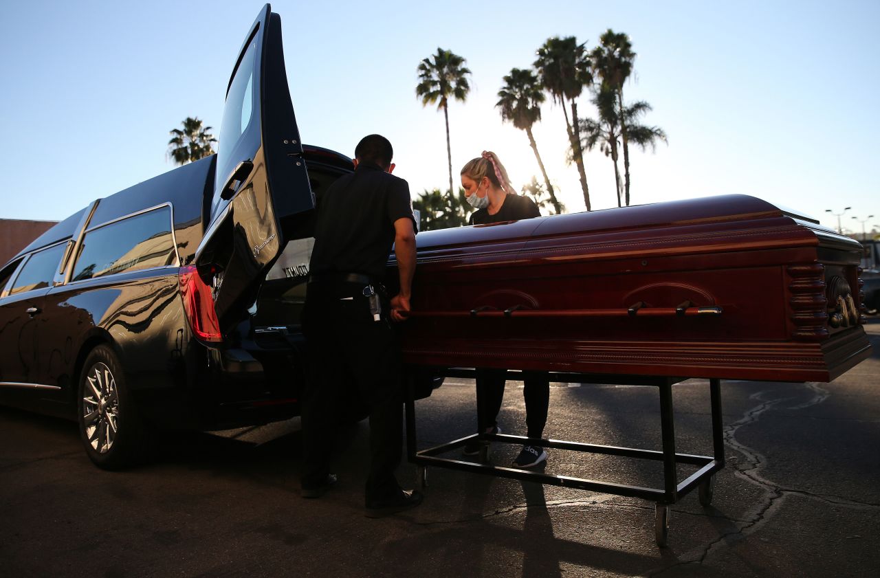 Embalmer and funeral director Kristy Oliver, right, and funeral attendant Sam Deras load the casket of someone said to have died after contracting Covid-19 into a hearse at East County Mortuary in El Cajon, California, on January 15.