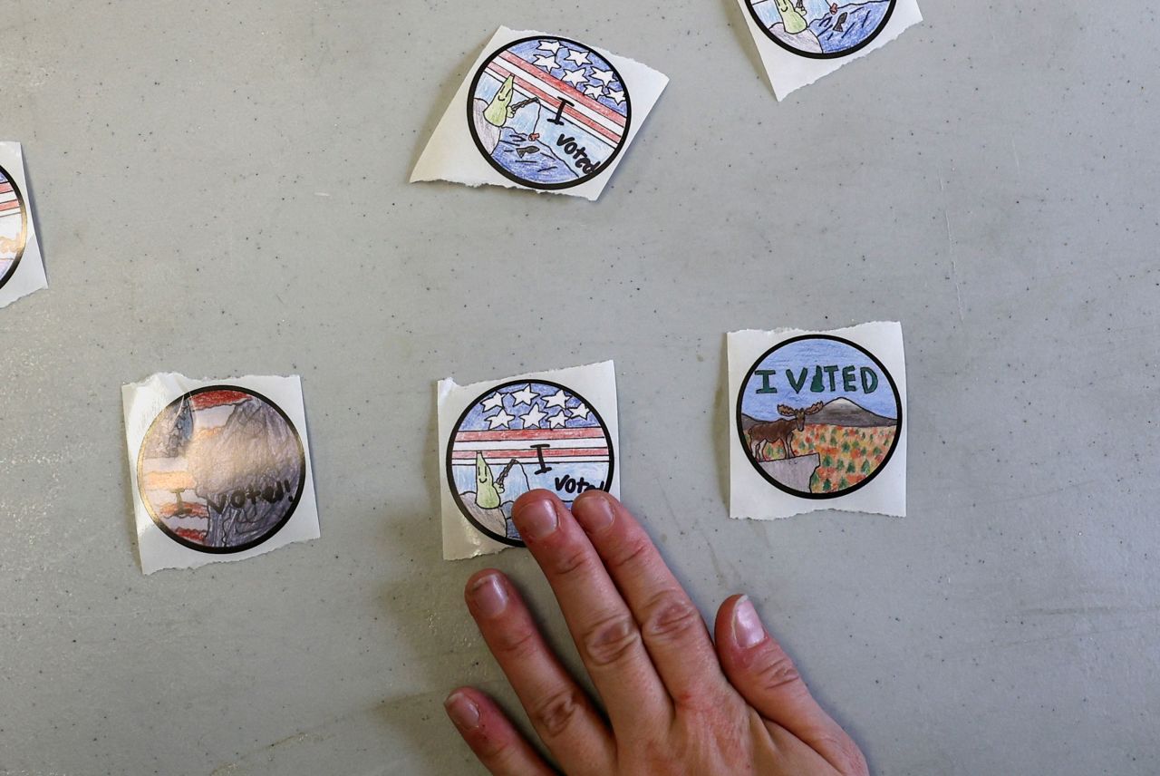 An election volunteer in Concord, New Hampshire, shows the winning stickers from a statewide design competition that was held for fourth-grade students.