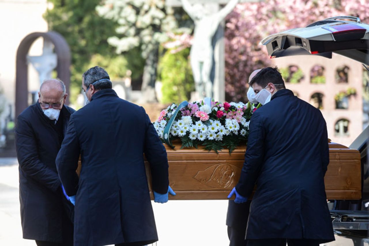 Undertakers wearing face masks unload a coffin out of a hearse on March 16 at the Monumental cemetery of Bergamo, Lombardy, as burials of people who died of the coronavirus are being conducted every half hour.