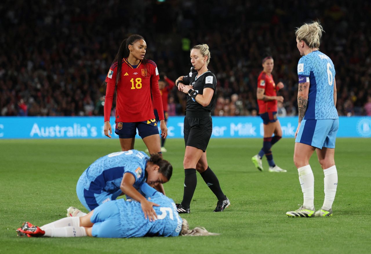 Spain's Salma Paralluelo is shown a yellow card by referee Tori Penso as England's Alex Greenwood reacts after sustaining an injury.