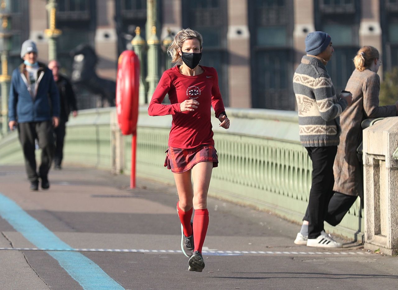 A woman wearing a face mask runs across the Westminster Bridge in London.