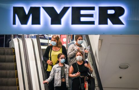 Shoppers wearing face masks ride an escalator as they exit the Myer store located in the Pitt Street Mall in Sydney, Australia, on December 26, 2020. 