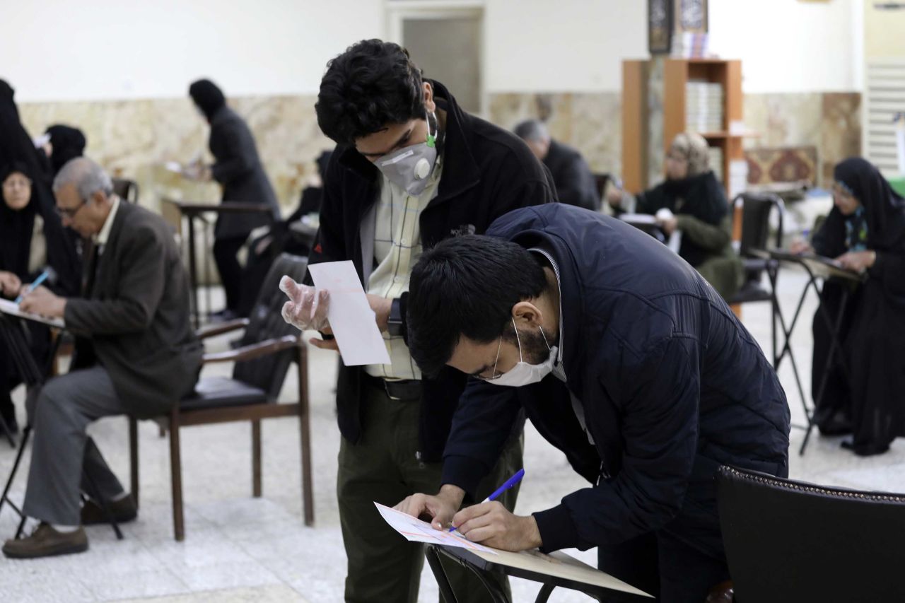 Voters with face masks fill out their ballots for the parliamentary elections at a polling station in Tehran, Iran, on Friday.