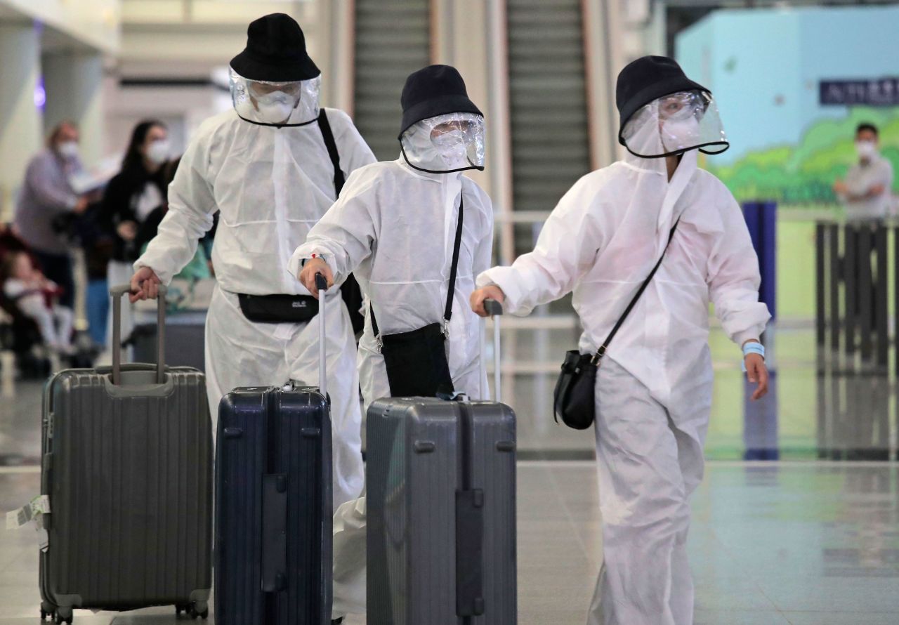 Passengers wear protective suits and face masks as they arrive at Hong Kong airport, Monday, March 23, 2020.