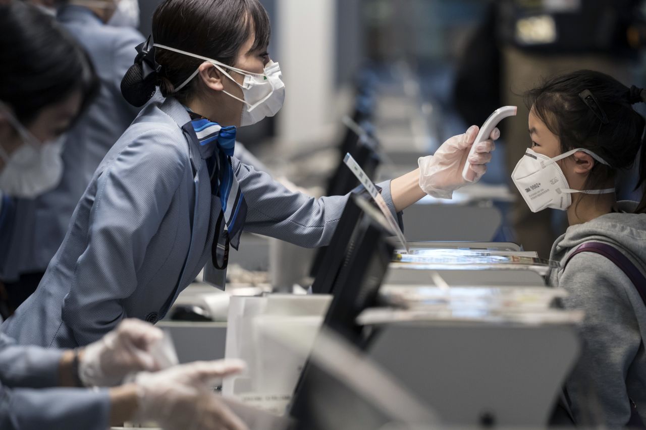 A passenger receives a temperature check at Haneda airport on January 31, 2020 in Tokyo, Japan.