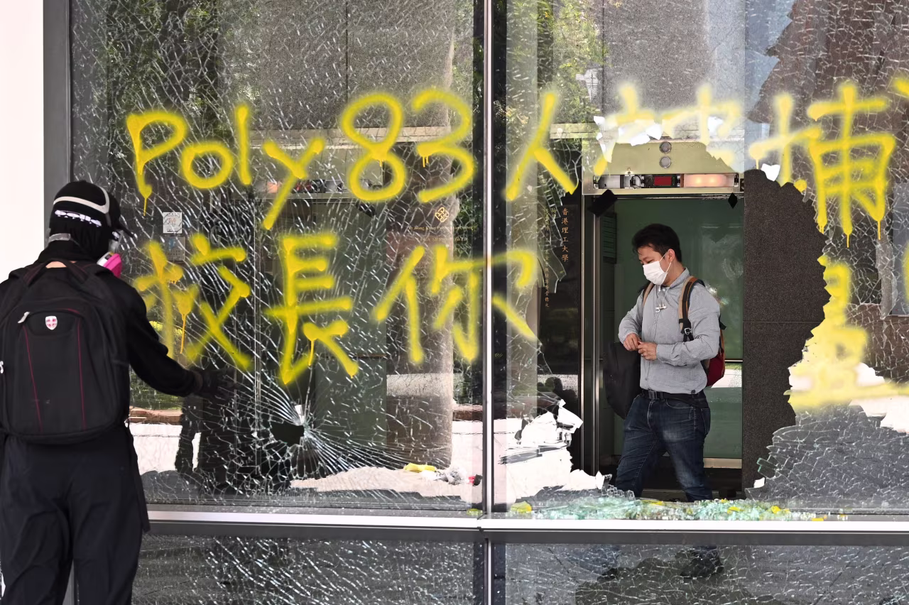A man (R) stands inside a building as the windows were smashed up in the campus of the Hong Kong Polytechnic University.
