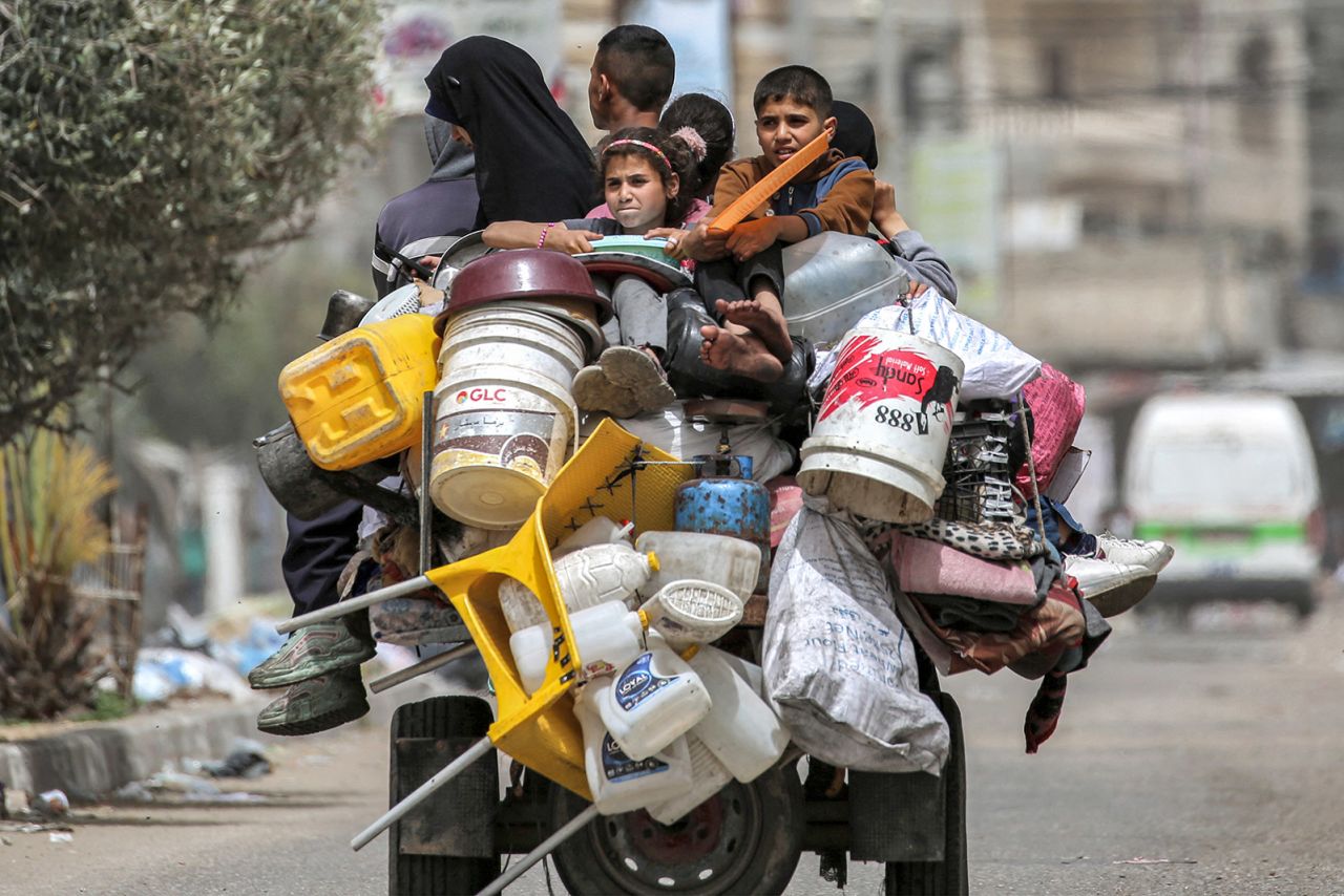 A man, woman and children ride in the back of a tricycle loaded with belongings and other items as they flee Rafah on May 11.