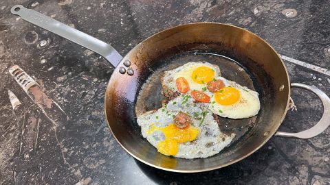 The de Buyer Mineral B 2 Handles carbon steel pan, with finished egg dish topped with tomato, and green onions.