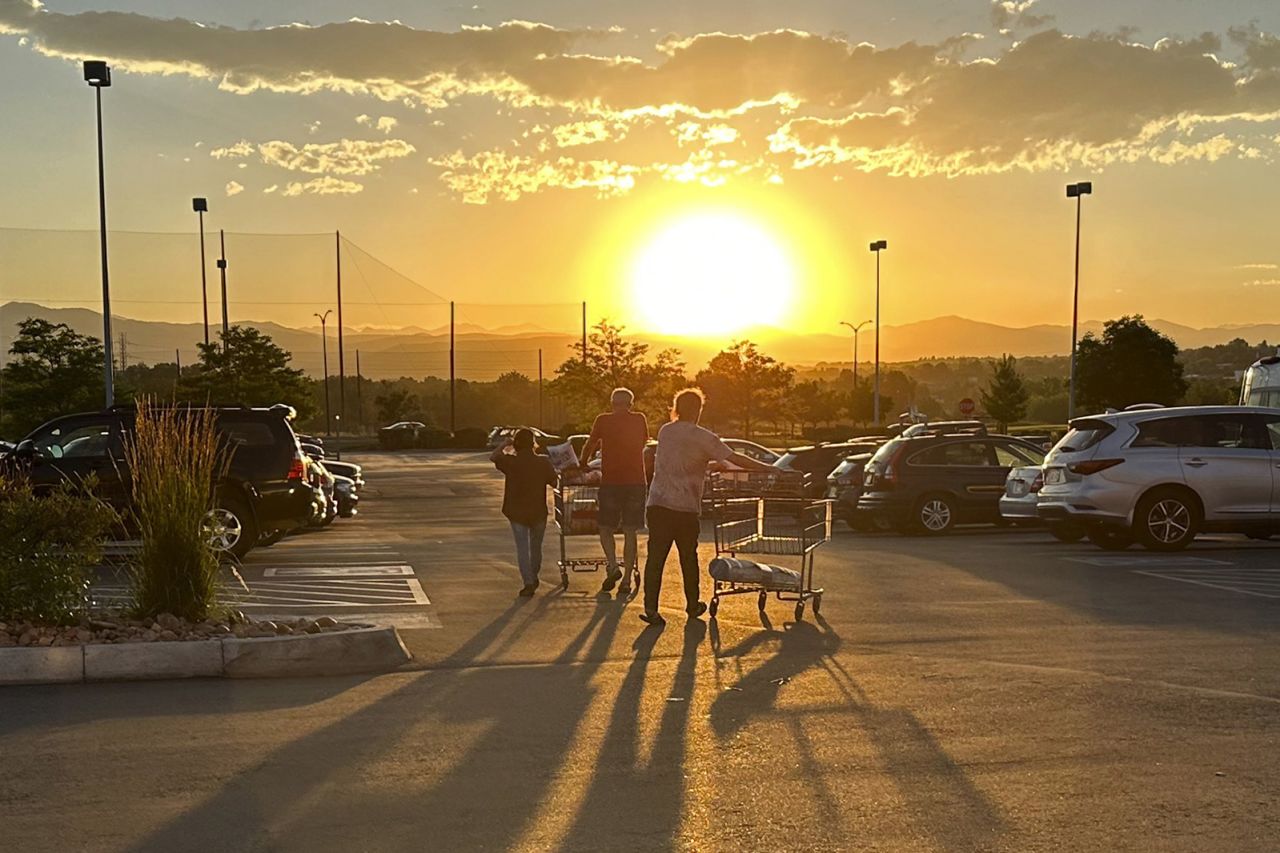 Shoppers cast long shadows as they head to their vehicles outside a Costco warehouse on July 11, 2023, in Sheridan, Colorado. 