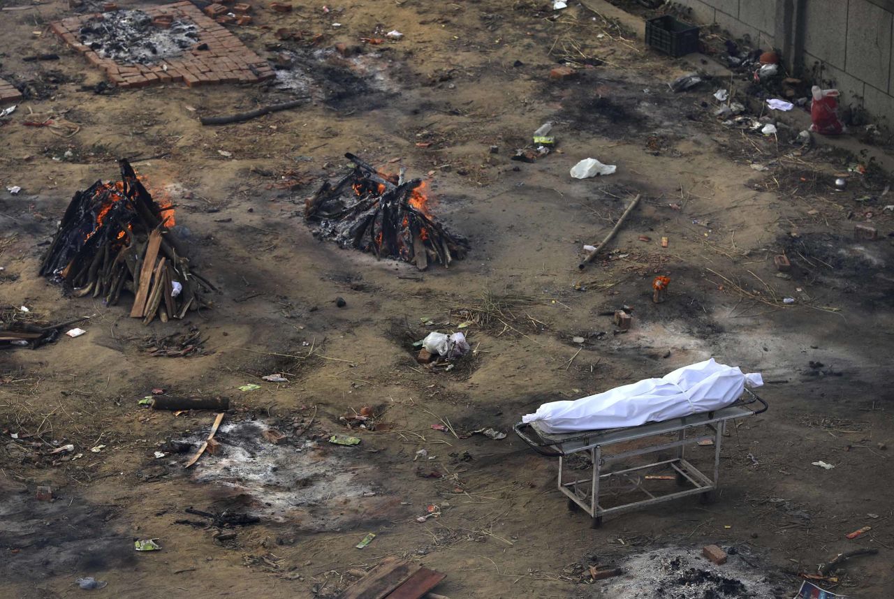 A body waiting for cremation is seen among funeral pyres of Covid-19 victims at a ground that has been converted into a mass crematorium in New Delhi, on April 21.