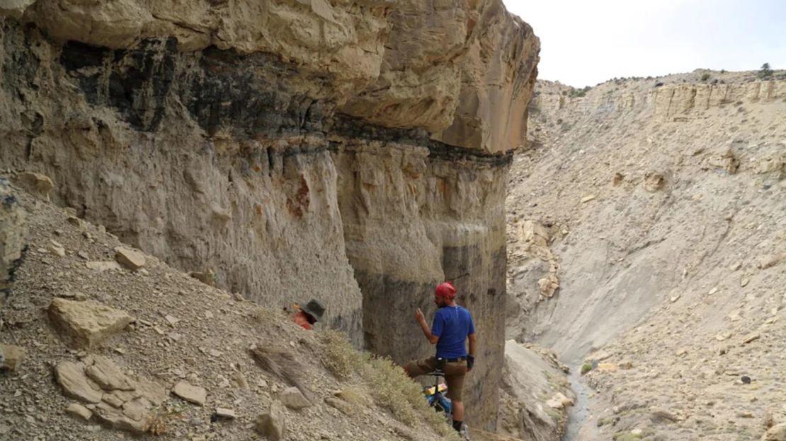 Un paleontólogo buscando fósiles de dinosaurios en rocas del Cretácico norteamericano.