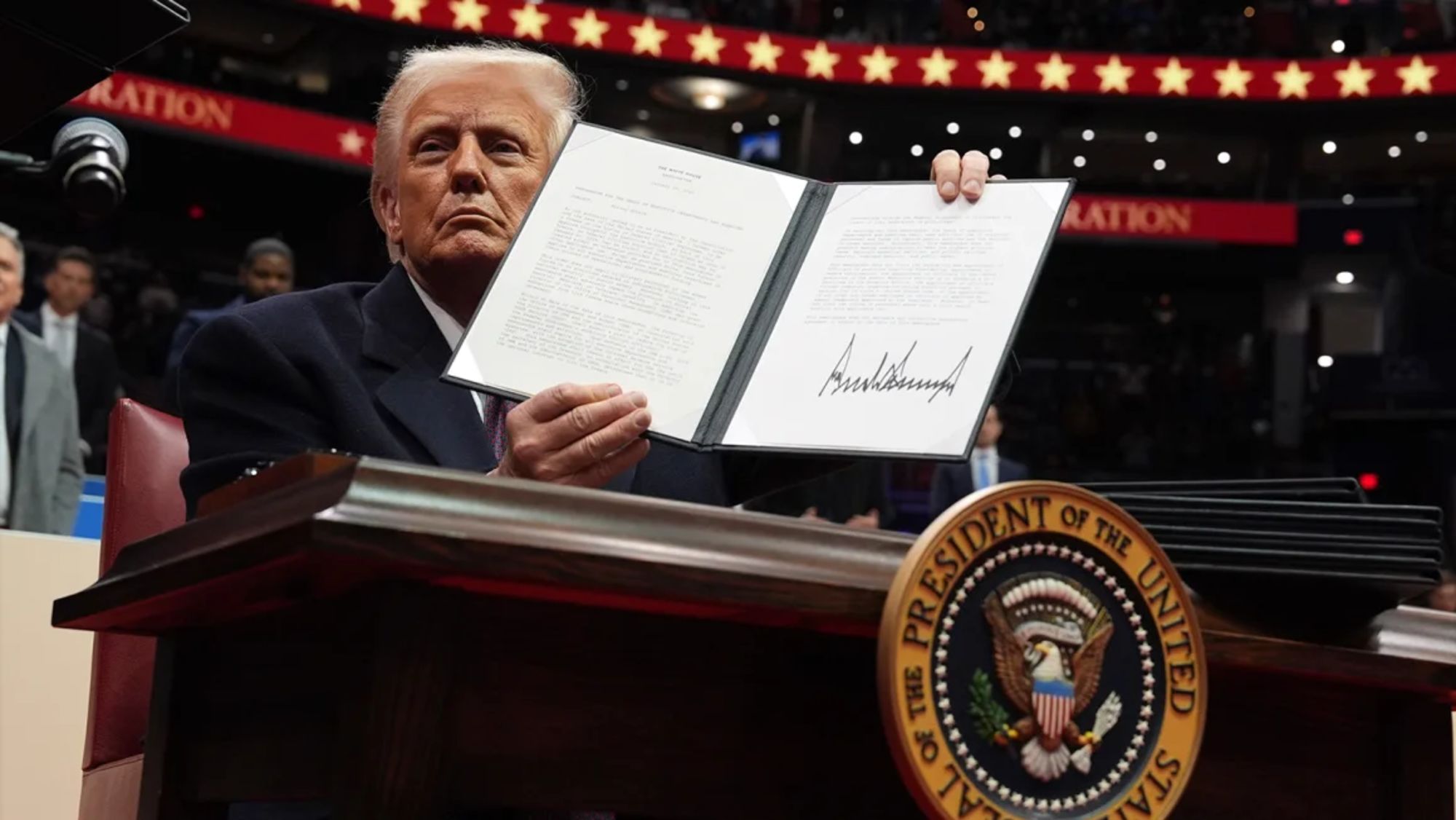 El presidente Donald Trump firma una orden ejecutiva mientras asiste a un desfile inaugural presidencial en el Capital One Arena, el 20 de enero de 2025, en Washington.