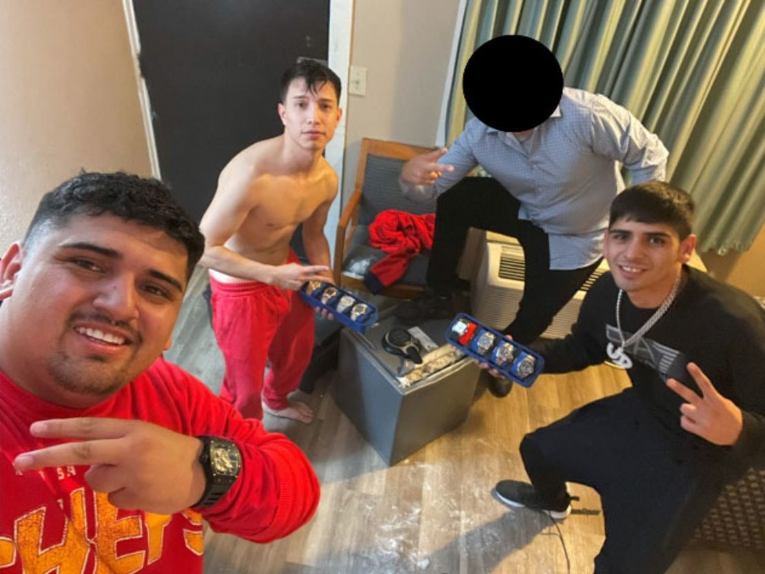 In this image released by the US Attorney’s Office, Middle District of Florida, Pablo Zuniga Cartes, Ignacio Zuniga Cartes, and Bastian Jimenez Freraut, along with a fourth individual whose face was blocked out by the FBI before the image’s release, pose with a collection of watches and a safe.