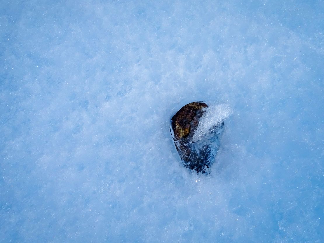 A meteorite lies partially in the ice in contrast with most samples collected while on the surface.
