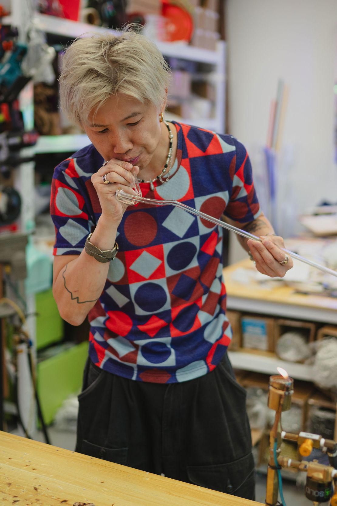 Jive Lau blows into a glass tube, shaping a piece of a new project.