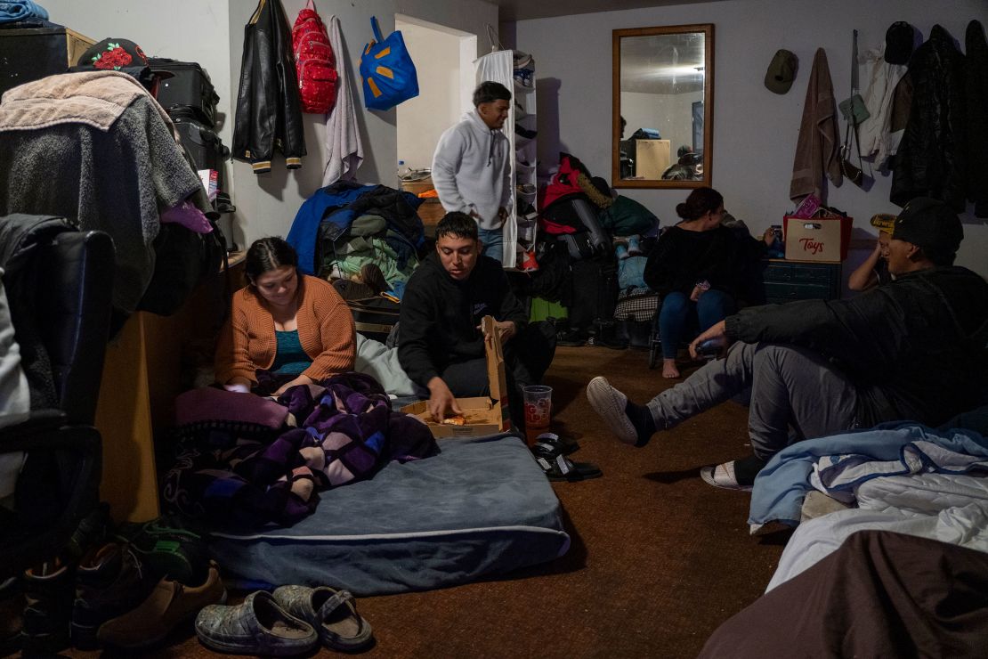 A group of people camp out in one of the rooms at Yong Prince’s motel. Carlo, center, eating pizza, said Prince had been like a mother to the migrants, cooking them breakfast every day before they went to look for work.