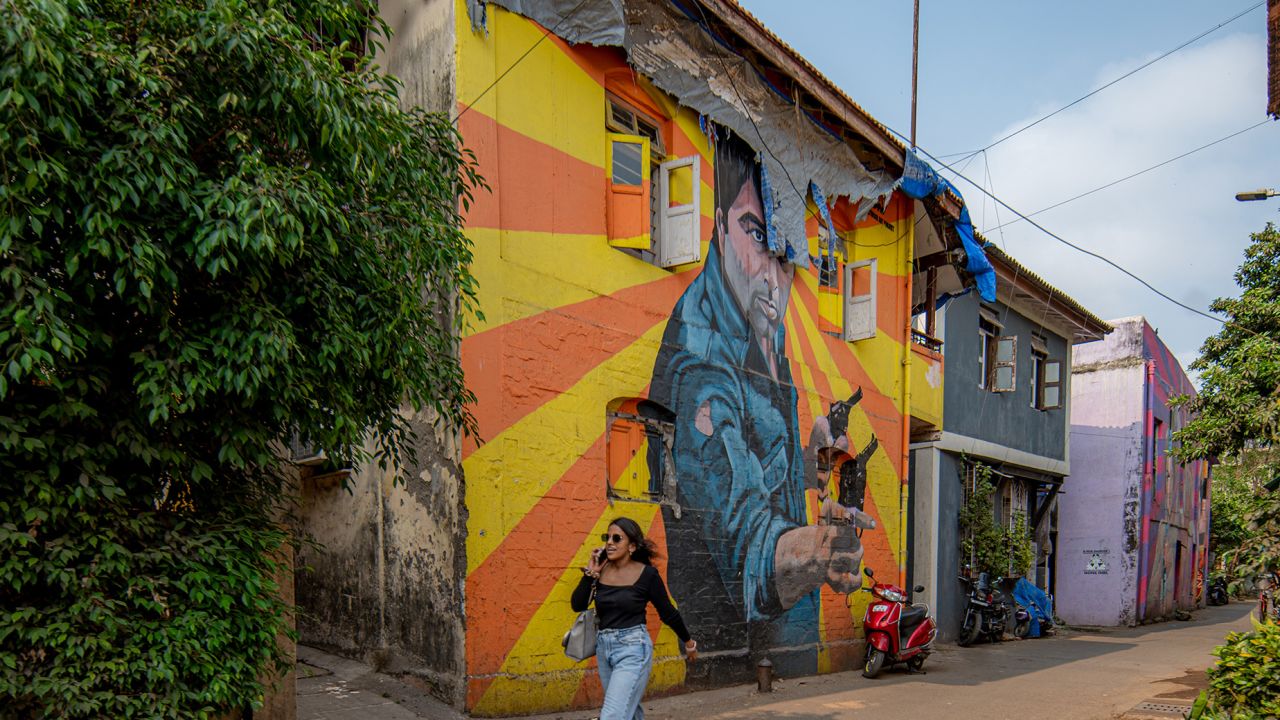 A woman walks past a mural portraying Bollywood Indian actor Dharmendra, in Mumbai, India, on April 17, 2024.