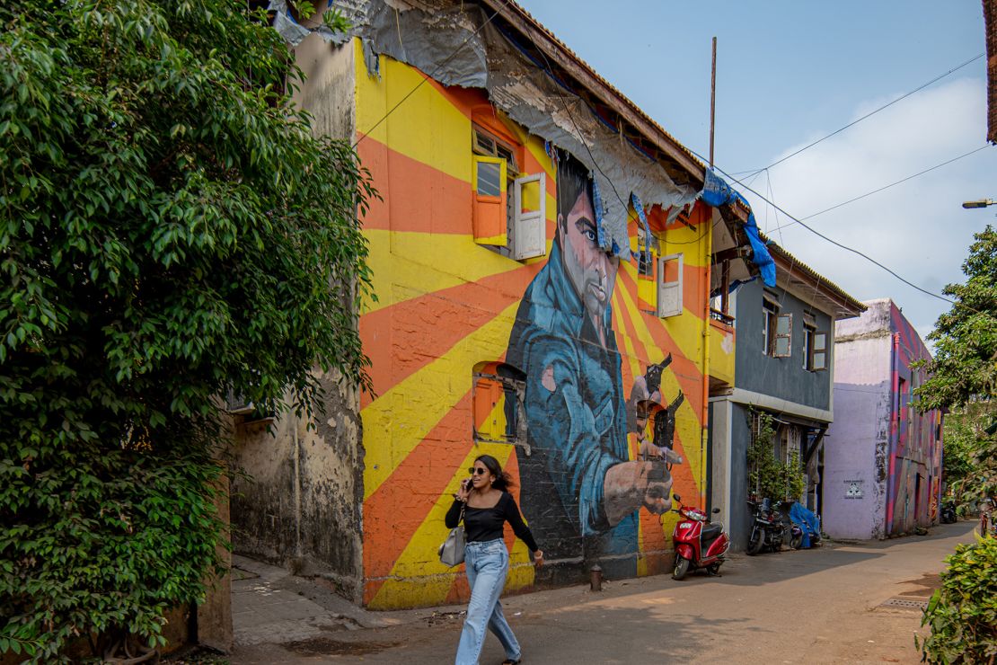 A woman walks past a mural portraying Bollywood Indian actor Dharmendra in Mumbai, India, on April 17, 2024.