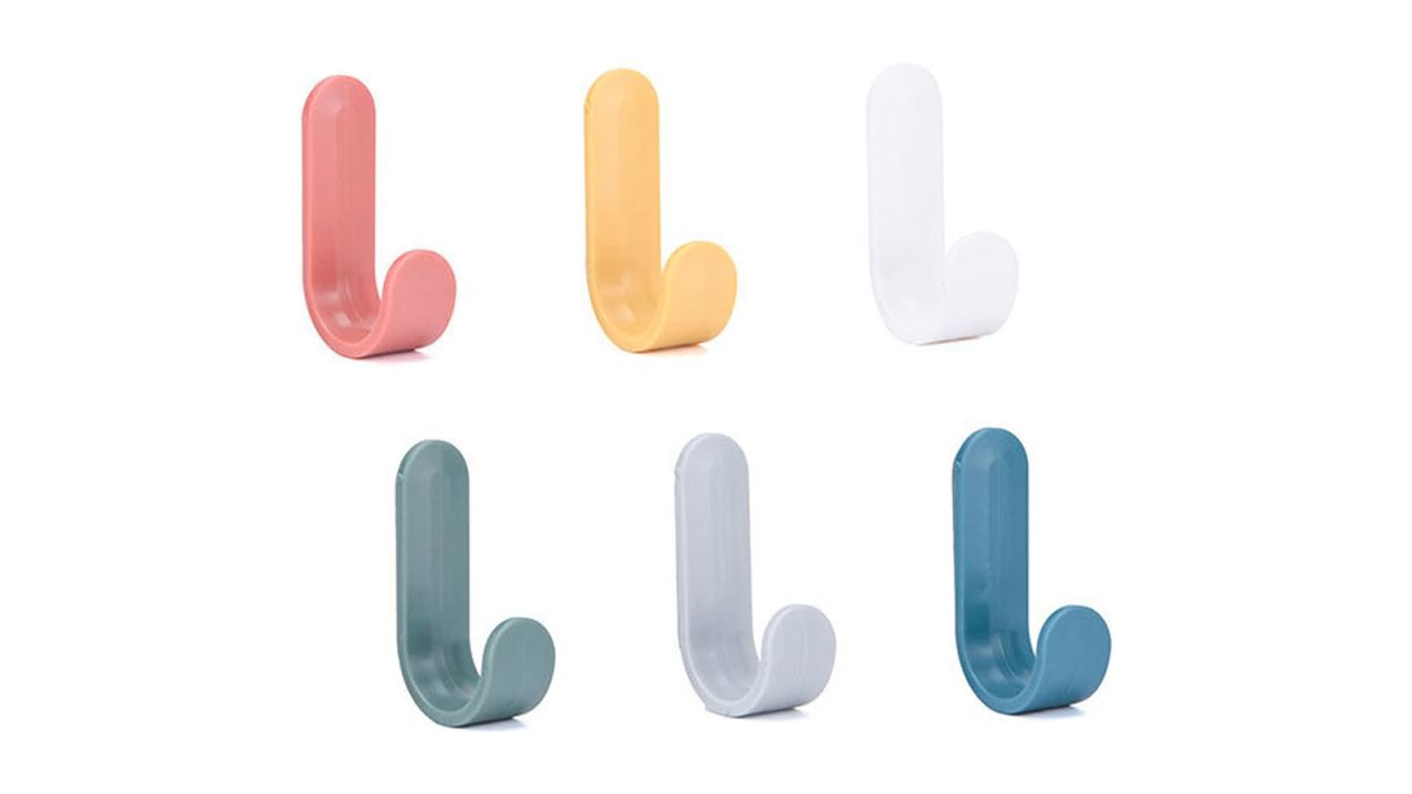 Six small adhesive hooks of various colors against a white background.