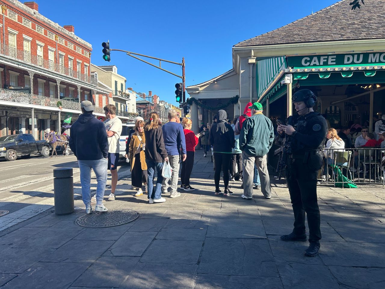 People walk outside Cafe du Monde in New Orleans with an armed police officer standing nearby on January 1.