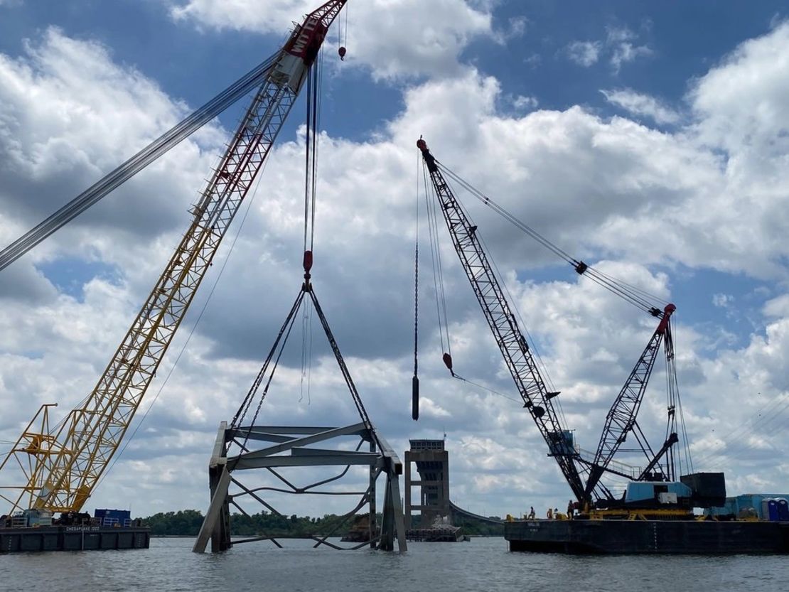 Cranes help remove a piece of the collapsed Francis Scott Key Bridge from the Patapsco River.