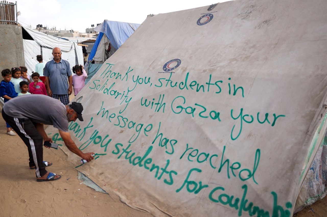 A man writes a message of thanks to students protesting in the US on a tent at a camp for displaced Palestinians in Rafah, Gaza, on April 27. 