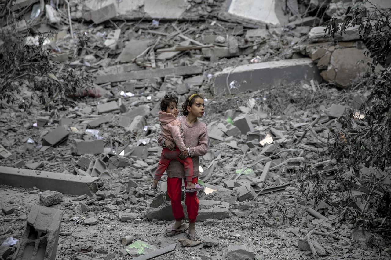 A Palestinian girl carries a child through the rubble of houses destroyed by Israeli bombardment in Gaza City on March 3. 