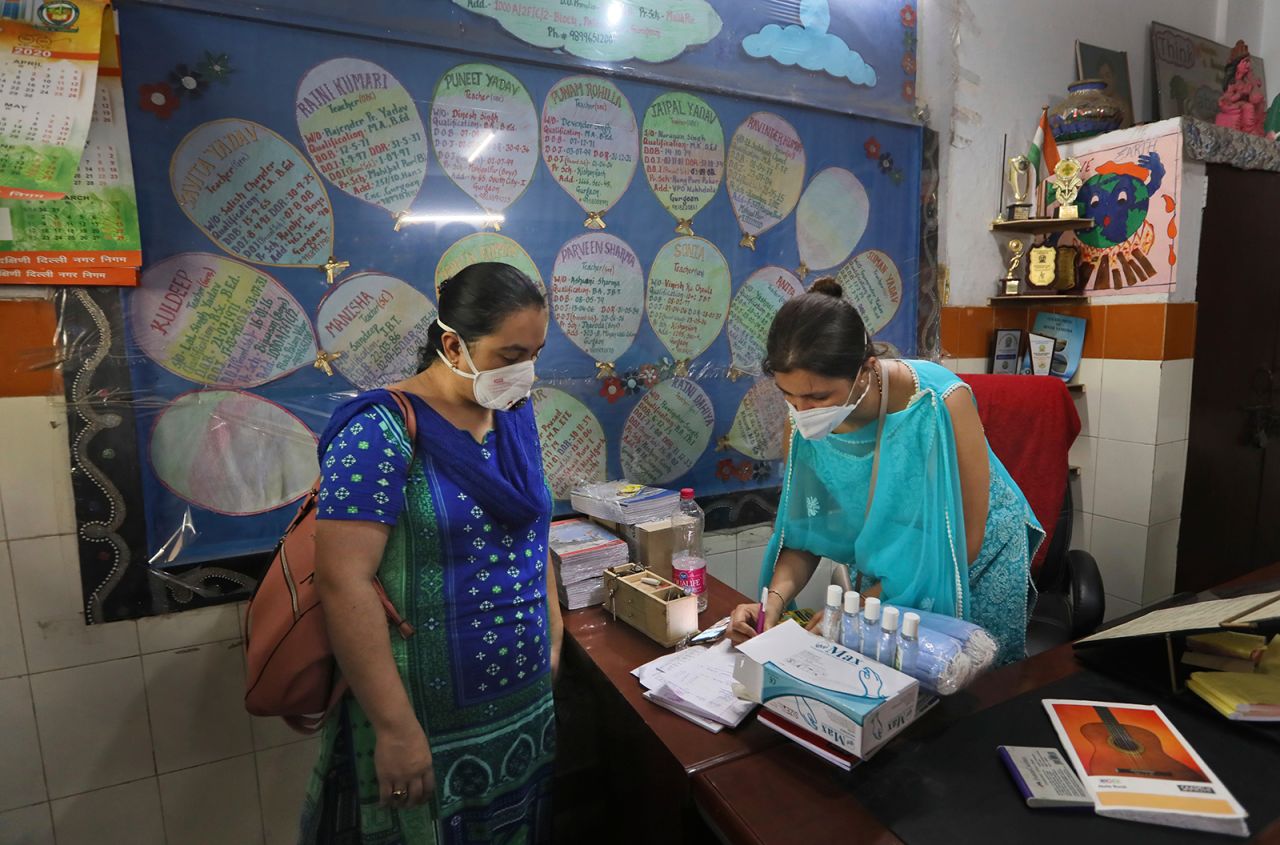 An Indian government school teacher notes down details to give a hand sanitizer to a fellow teacher who has been assigned to take a survey at a residential neighborhood in New Delhi, India on June 27.