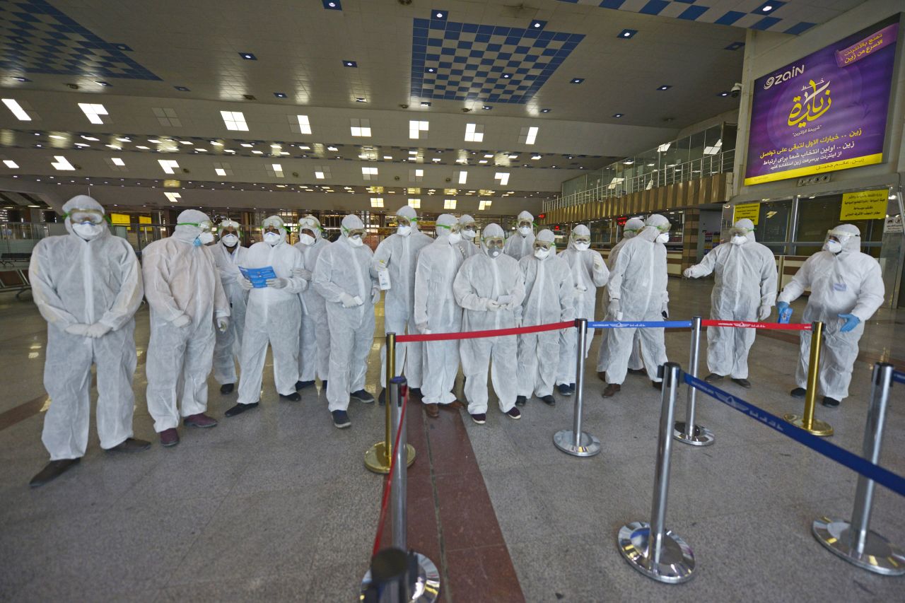 Medical staff in protective gear wait for Iraqi passengers returning from Iran at Najaf International Airport on March 5, 2020.?