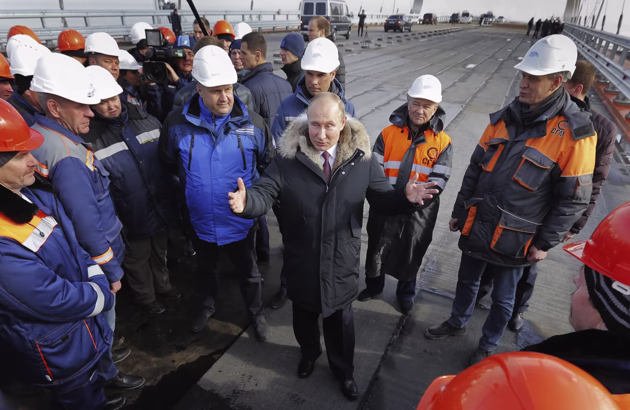 Russian President Vladimir Putin, centre, speaks with workers visiting the road section of the road-rail bridge linking Crimea to mainland Russia near Kerch, Crimea, on March 14, 2018. Putin hailed the bridge, which is set to be completed later this year, as a major engineering achievement and praised those involved in its construction.