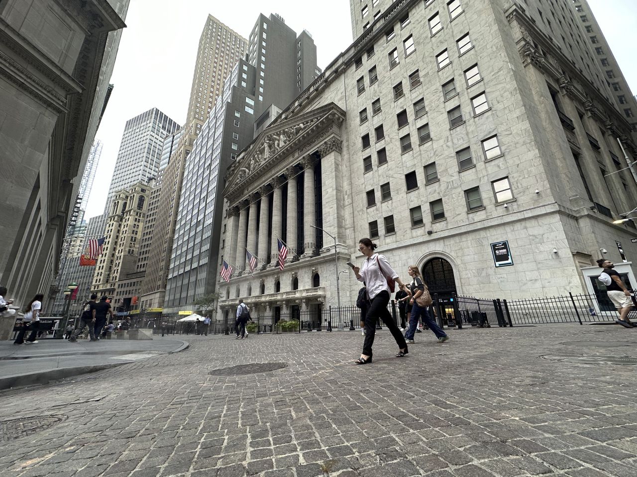 People pass the New York Stock Exchange on July 30.