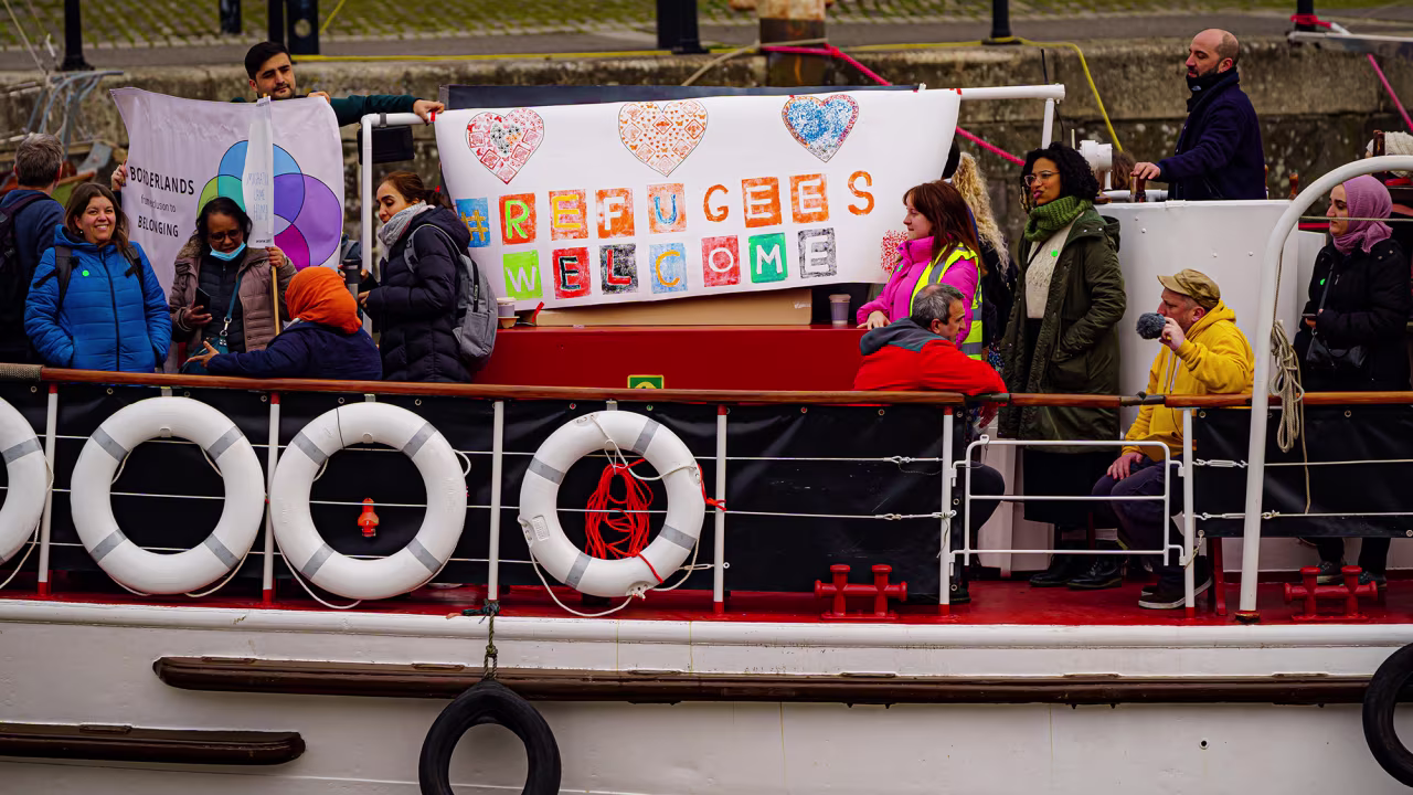 People wave banners and hearts aboard a small flotilla of boats leaving Bristol harbour in support of Ukrainian refugees during a day of national action on March 21.