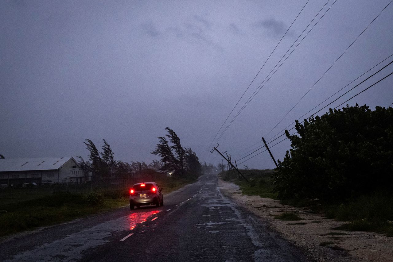 A car in the rain drives past a collapsed post as Hurricane Beryl hits the southern coast of the island, in Kingston, Jamaica, on July 3.