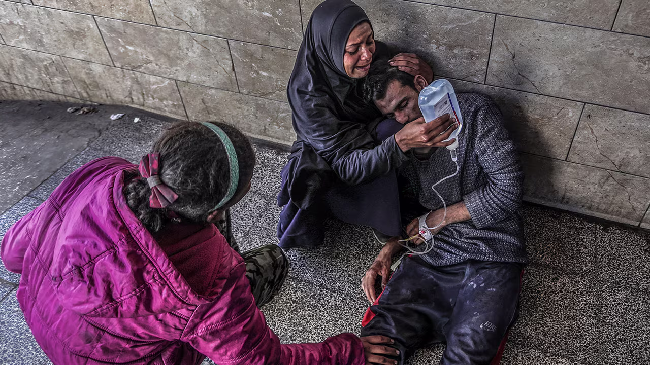 A Palestinian woman holds a glucose solution for her relative, who was injured in an Israeli air strike near a warehouse of the United Nations Relief and Works Agency for Palestine Refugees, at Al-Najjar Hospital in Rafah, Gaza. 