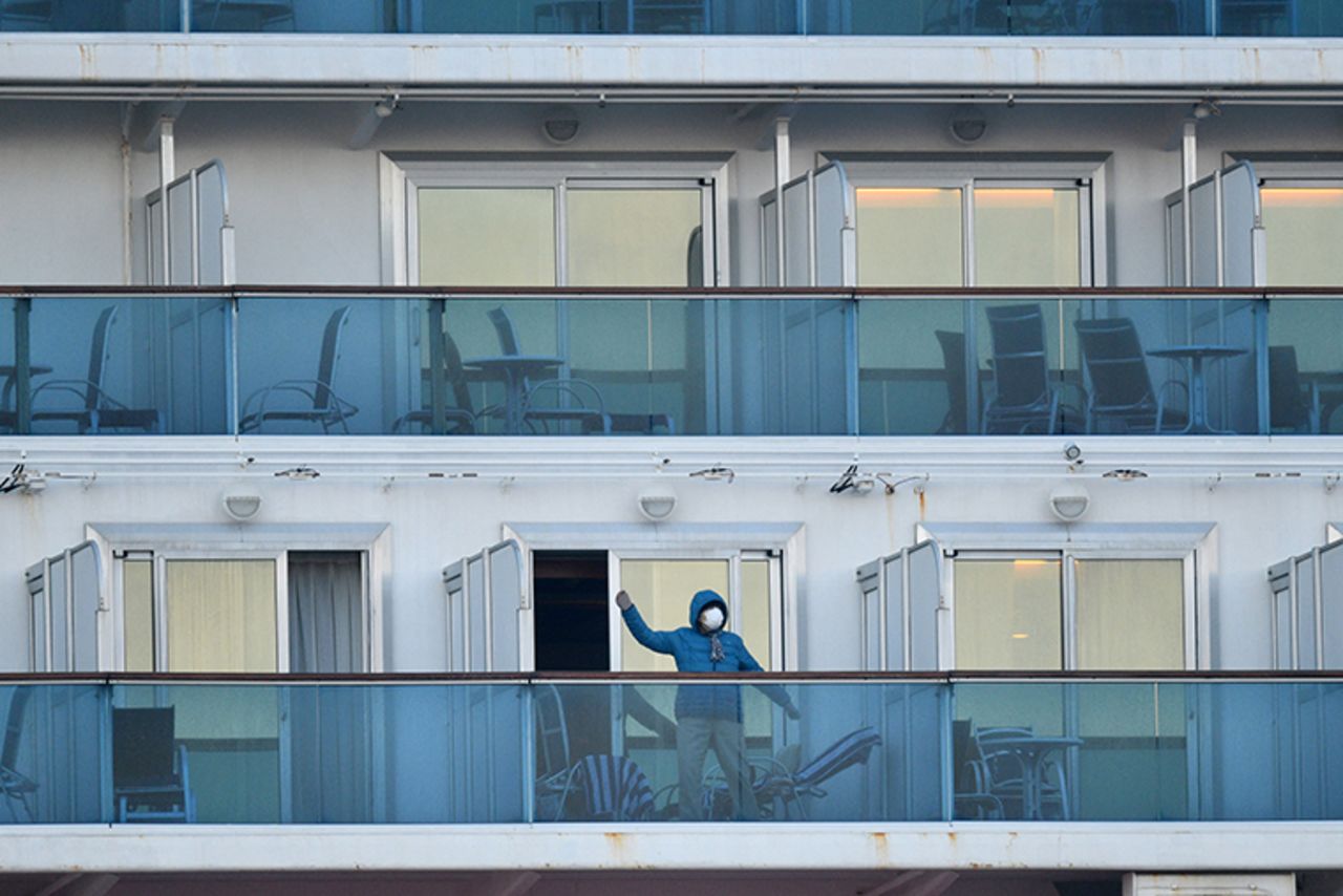 A passenger is seen on a balconies of the Diamond Princess cruise ship at the Daikaku Pier Cruise Terminal in Yokohama port onThursday, February 13.