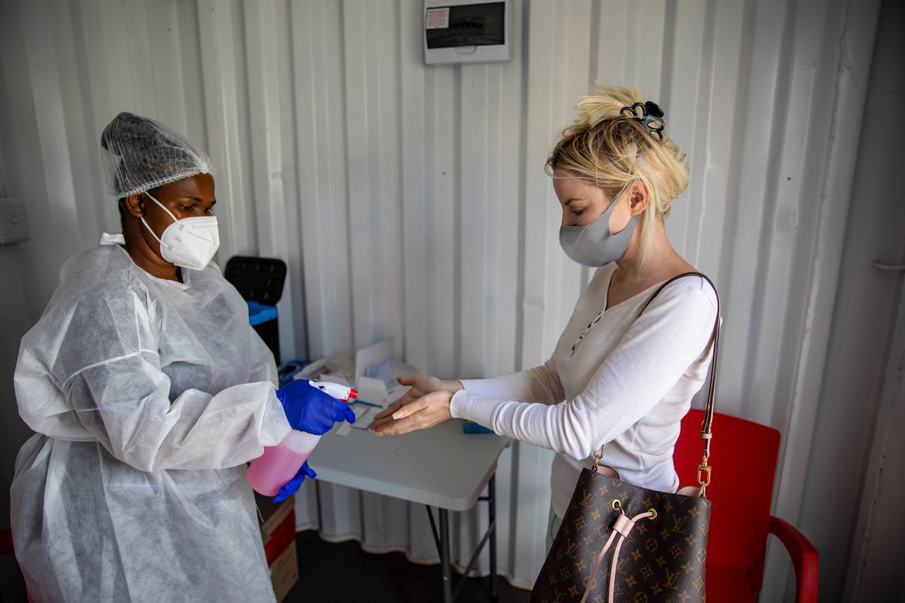 A health worker sanitizes a resident's hands at a Testaro Covid-19 mobile testing site outside Richmond Corner shopping center in the Milnerton district of Cape Town, South Africa, on Thursday, Dec. 2, 2021. 