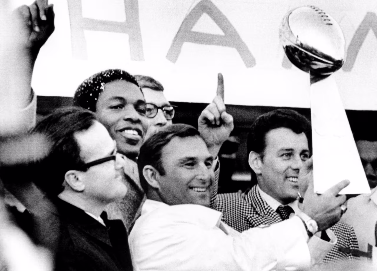 Head coach Hank Stram of the Kansas City Chiefs holds the Super Bowl trophy as owner Lamar Hunt (L), Otis Taylor and Len Dawson (R) look on during the Chiefs rally after their Super Bowl IV victory over the Minnesota Vikings on January 12, 1970.