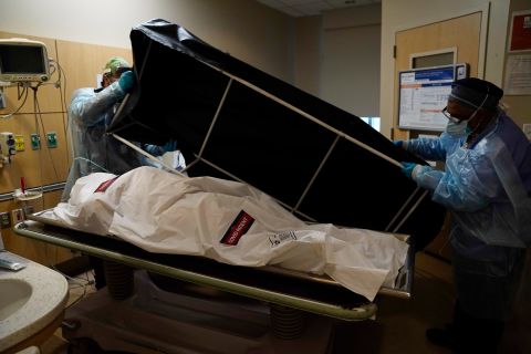 Transporters Miguel Lopez, right, and Noe Meza prepare to move a body of a COVID-19 victim to a morgue at Providence Holy Cross Medical Center in Los Angeles on January 9. 