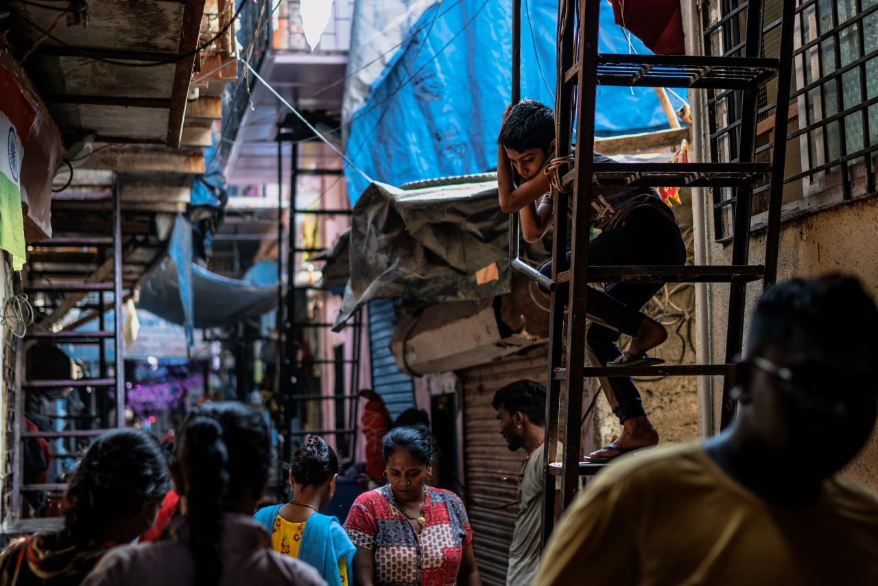 Kilare walks along a crowded alley as she goes back home after her daytime cleaning shift — with more shifts later in the evening.