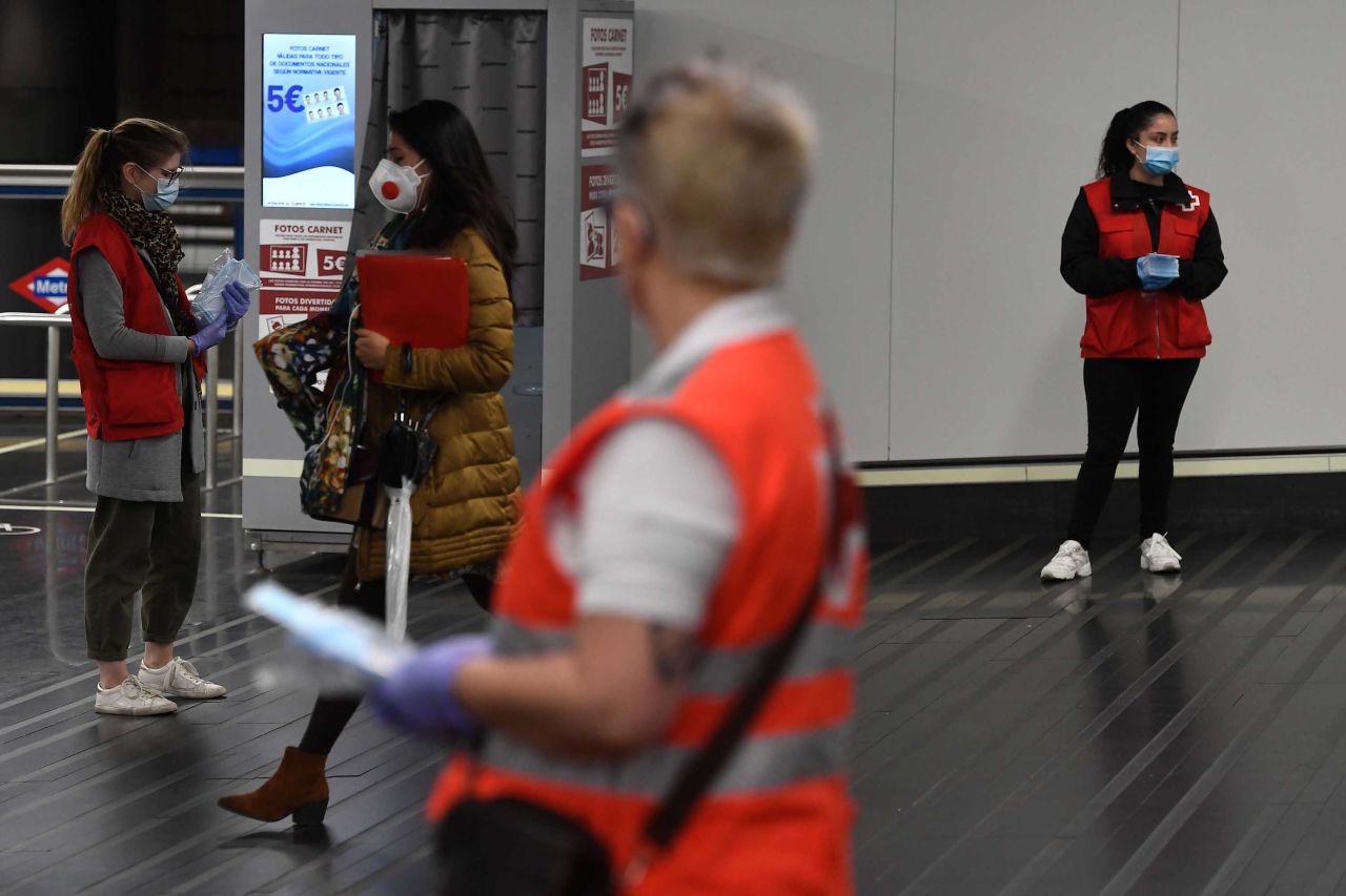 Spanish Red Cross volunteers distribute face masks at the Chamartin Station in Madrid on April 13. Some companies are set to resume operations after the government lifted some of the country's lockdown restrictions.