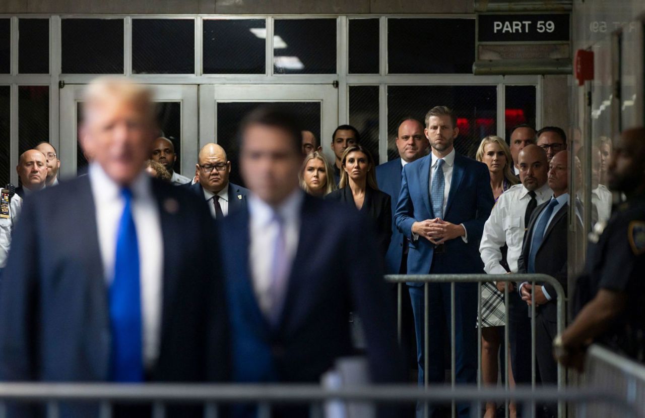 Trump's son Eric, seen fourth from the right with his fingers interlocked, listens as his dad speaks to the media after the verdict on May 30. 