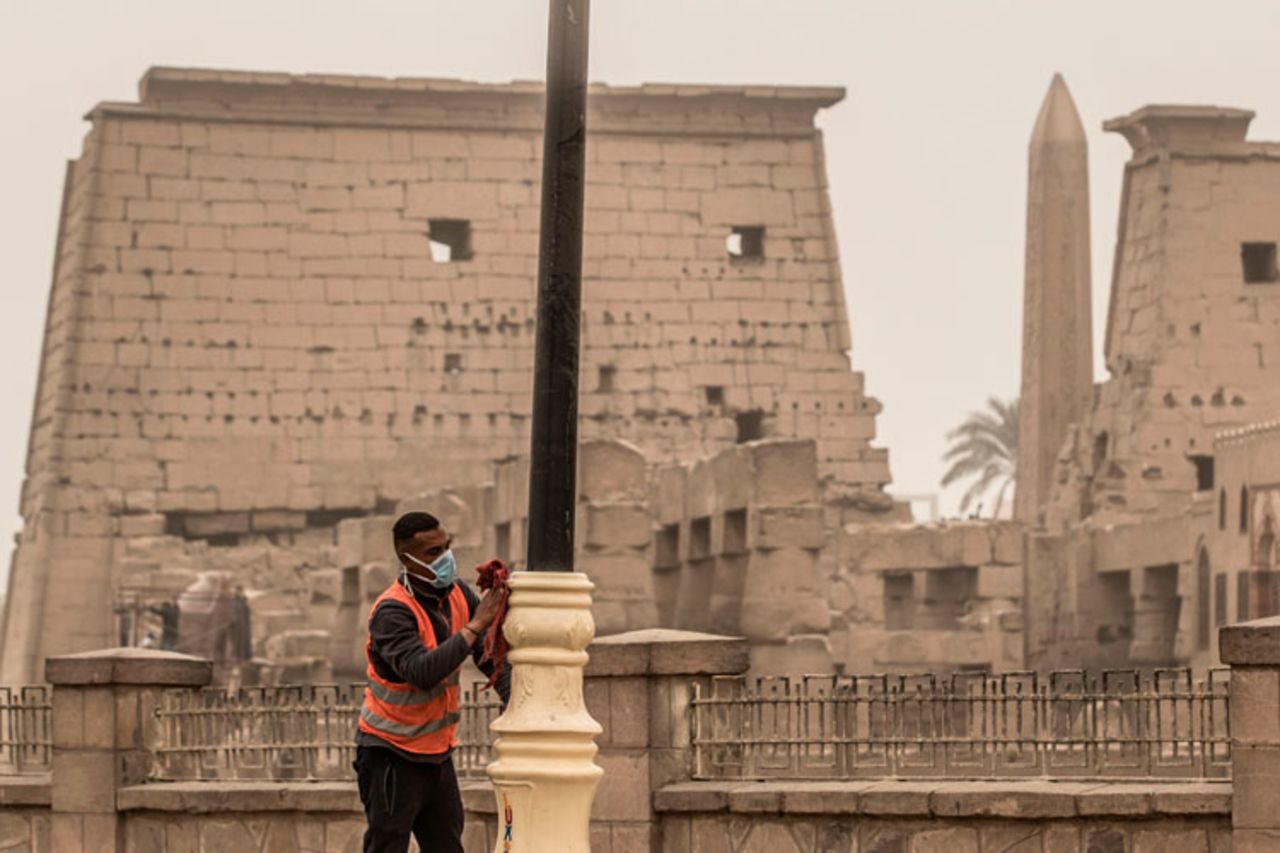 A worker cleans lamp posts amid a sandstorm and coronavirus fears outside the Luxor Temple in Egypt's southern city of Luxor on March 12.