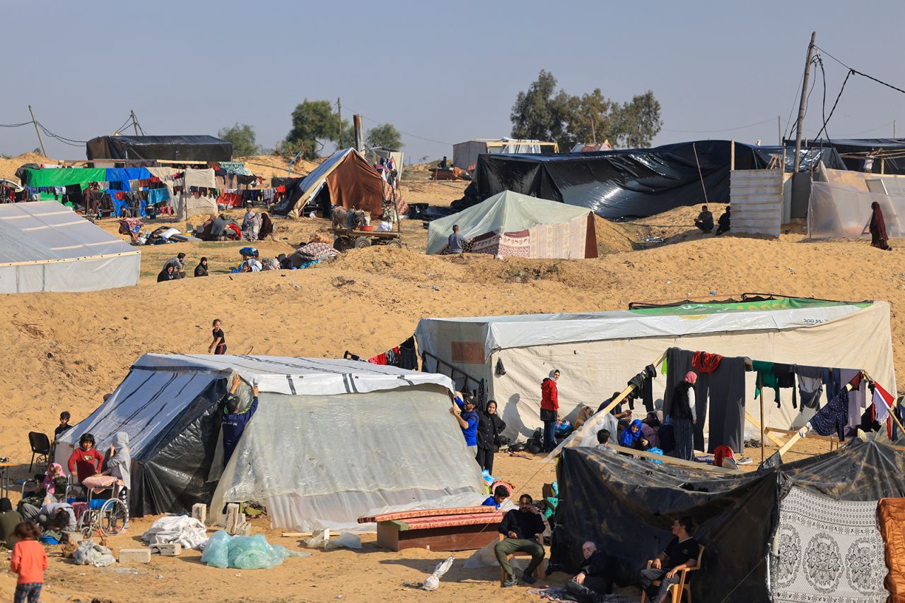 Displaced Palestinians who fled from Khan Younis, sit outside makeshift shelters at a camp in Rafah in the southern Gaza Strip on December 4.