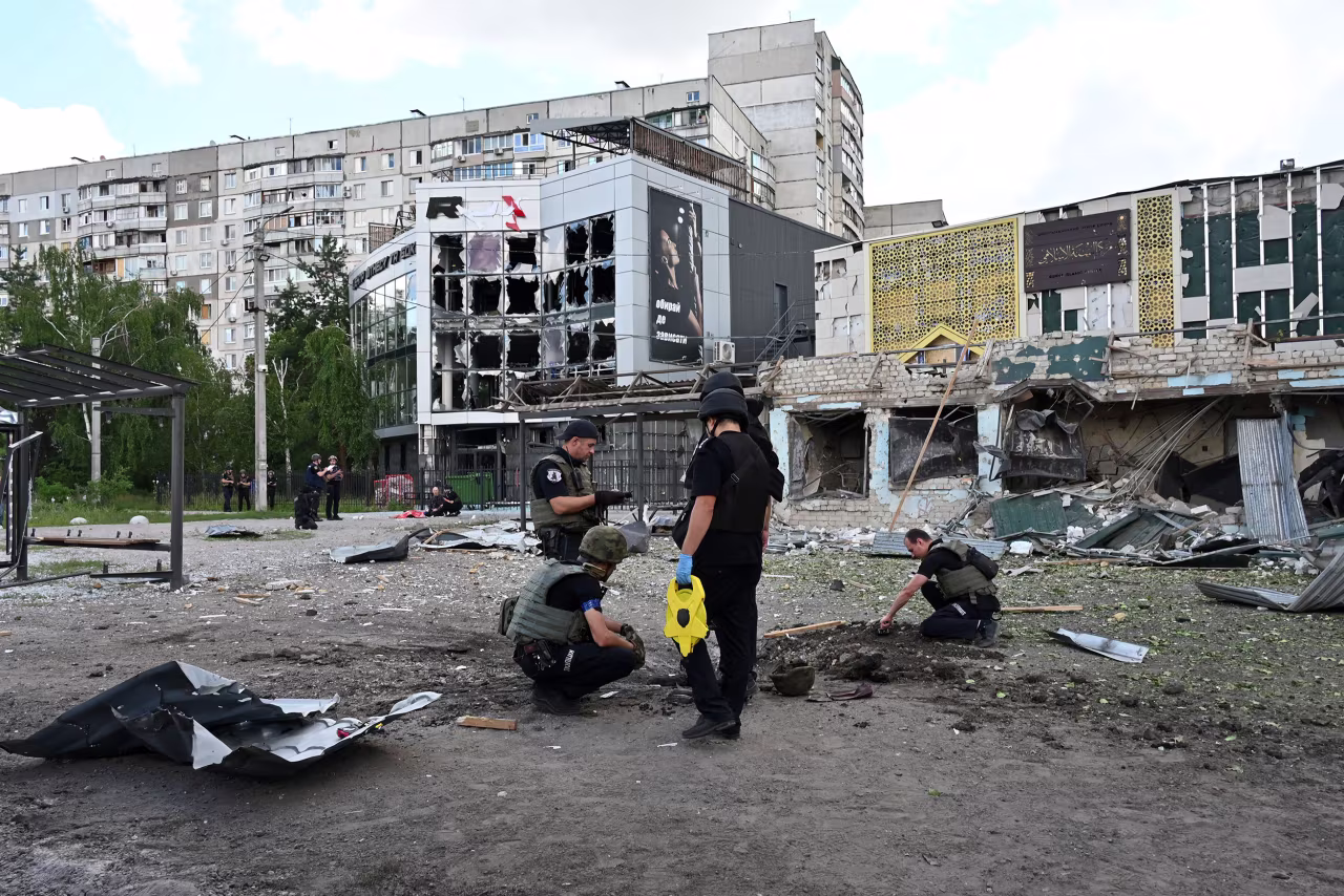 Police experts examine a crater left by a Russian missile strike at a bus stop in Saltivskyi, a northern district of of Kharkiv on July 20.